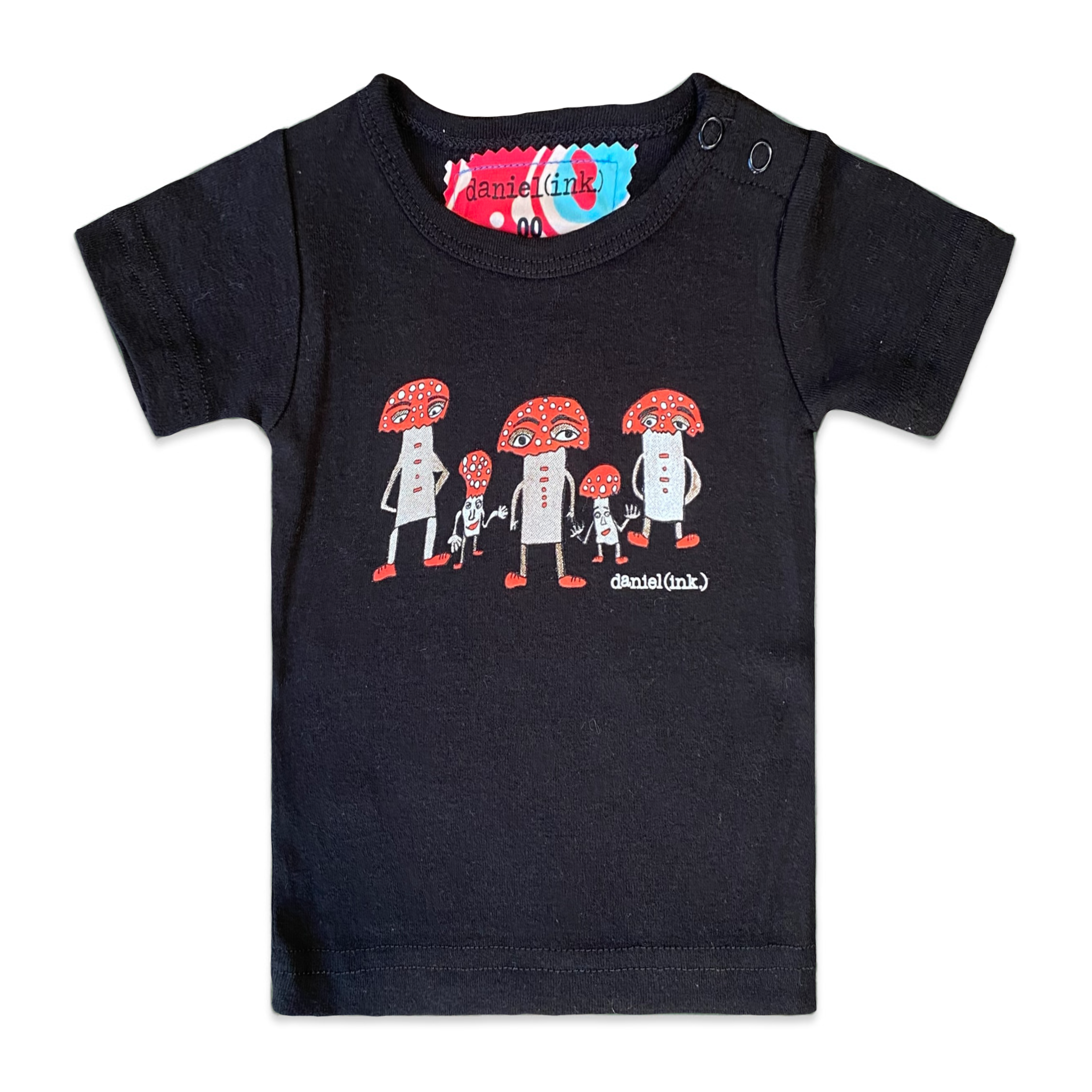 Black short sleeve babies' t-shirt featuring a hand drawn image of three large and two small mushroom humanoid figures. The mushroom figures have red heads and red shoes and red buttons which spell "magic" in morse code. The t-shirt has a red, white, and blue fabric label on the back of the neck and has two black press studs on the left shoulder. 