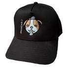 Black snapback cap featuring an embroidered image of a dog's face in brown and white. The dog has a round head, floppy ears, wide eyes, and its tongue is sticking out. The name daniel(ink.) is embroidered in silver thread next to the dog's face. 