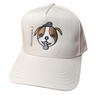 Ecru snapback cap featuring an embroidered image of a dog's face in brown and white. The dog has a round head, floppy ears, wide eyes, and its tongue is sticking out. The name daniel(ink.) is embroidered in silver thread next to the dog's face. 