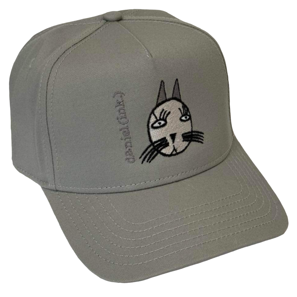 Storm snapback cap featuring an embroidered image of a cat's head in silver. The cat has long pointy ears, long eyelashes, and long whiskers coloured black. The name daniel(ink.) is embroidered in silver thread next to the cat's head. 